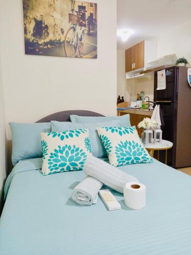 a blue bed with towels and a cup of coffee on it at Norman Condominium Unit Rental in Dumaguete