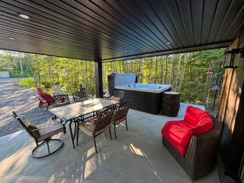a patio with a table and chairs and a hot tub at Spa - Chalet Sur Les Sentiers du Pic-Bois in Adstock