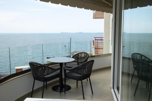 a balcony with a table and chairs and the ocean at Rayan Luxury Apartament Vlore in Vlorë