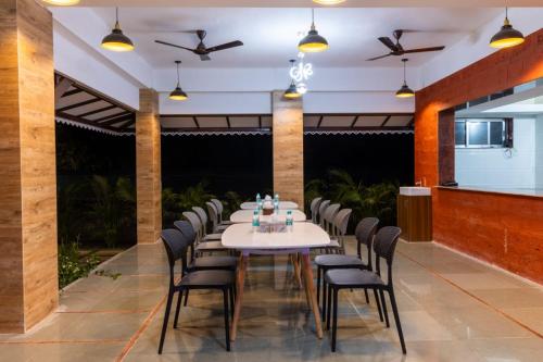 a long dining room with a white table and chairs at Green House Resort by Green Apple Stays 