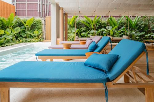a group of blue lounge chairs next to a pool at VELA be Bangkok Siam in Bangkok