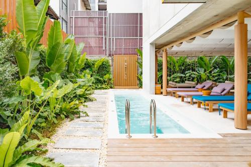 an outdoor pool with chaise lounge chairs and a house at VELA be Bangkok Siam in Bangkok