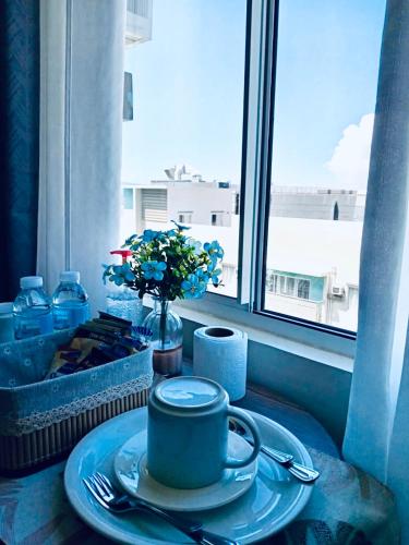 a table with a plate with a coffee cup and a window at Norman Condominium Unit Rental in Dumaguete
