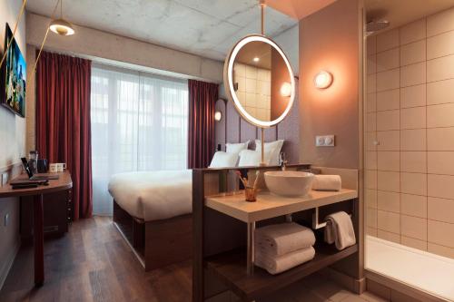 a bathroom with a bed and a sink and a mirror at lyf Gambetta Paris in Paris