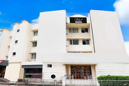 a white building with a black sign on it at Collection O Vashi formerly Blue Diamond in Turambhe