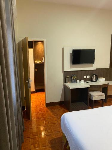 a hotel room with a bed and a desk and a television at Soeltan Luxe Hotel Lampung in Bandar Lampung