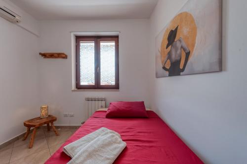 Un dormitorio con una cama roja y una ventana. en Dimora Green, en Lecce