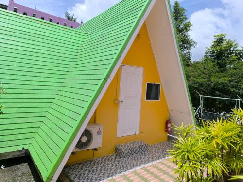 a green roof on a yellow house with a door at Ban Rai Rabeang Mok in Khao Kho