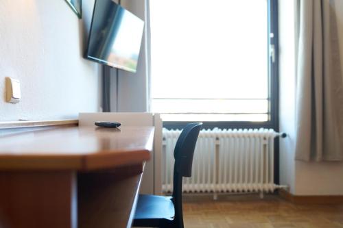 a desk with a chair and a television in a room at Monteurzimmer für bis zu 26 Personen in Straubing low budget mit Gemeinschaftsküche NEU in Straubing