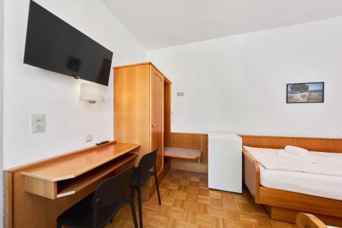 a room with a bed and a desk with a television at Monteurzimmer für bis zu 26 Personen in Straubing low budget mit Gemeinschaftsküche NEU in Straubing