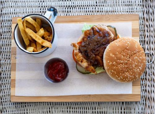 a hamburger and french fries on a wooden tray at Boulders Beach Hotel, Cafe and Curio shop in Simonʼs Town