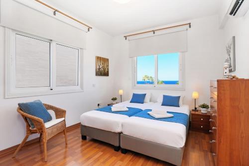 Un dormitorio con una cama y una silla y dos ventanas. en Villa Celine, en Protaras