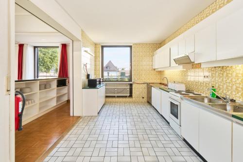 a kitchen with white cabinets and a tile floor at Monteurzimmer für bis zu 26 Personen in Straubing low budget mit Gemeinschaftsküche NEU in Straubing