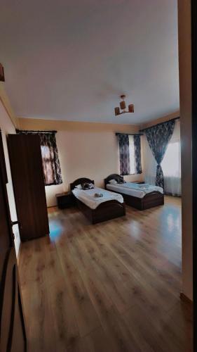a large room with two beds and a wooden floor at Agropensiunea Izana in Drăguţeşti