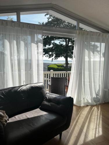 a black leather couch in a living room with a window at 43 Harbour View in Poole