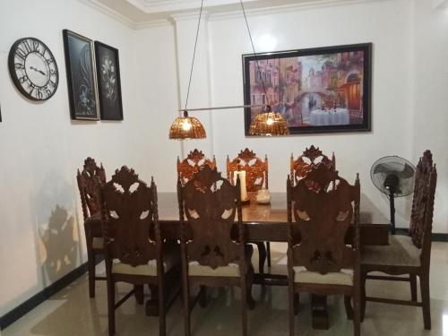 a dining room with a table and chairs and a clock at Leizel's Bed & Breakfast in Palompon