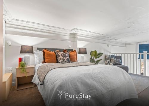 a bedroom with a king sized bed with orange pillows at Stylish Flat in Central Leeds with Mezzanine Room Sleeps 4 by PureStay in Central Station
