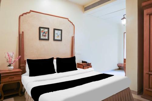 a bedroom with a large white bed with black pillows at Collection O Baner Road Pune formerly Hotel Rajwada in Dāpuri