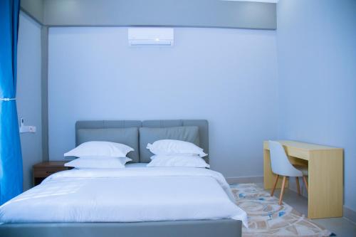 a bed in a room with a desk and a bed sidx sidx sidx at Eastern City Apartments in Dodoma