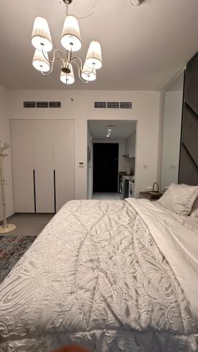 a bedroom with a large white bed with a chandelier at Aljada -Sharjah in Sharjah