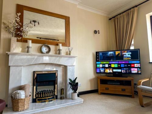 a living room with a tv and a fireplace at Maesllan - A Spacious Holiday Home in Porthcawl - 5 bedrooms, sleeps up to 10 people in Porthcawl