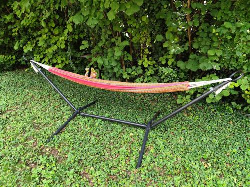 a hammock with a dog sitting in it on the grass at Chez Lily et Fred in Châlons-en-Champagne
