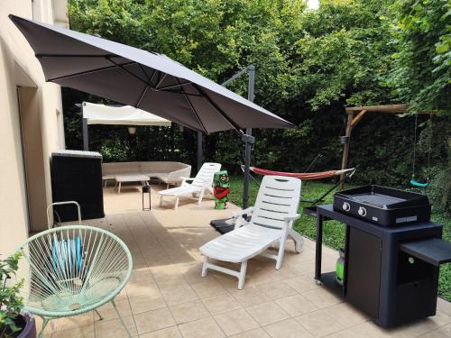 a patio with chairs and an umbrella and a grill at Chez Lily et Fred in Châlons-en-Champagne