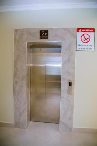 a metal elevator in a building with a sign on it at Eastern City Apartments in Dodoma