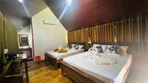 a bedroom with two beds with towels on them at The Rock & Paddy Resort in Sigiriya