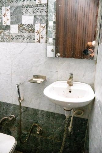 a bathroom with a sink and a mirror and a toilet at Ved Hotel & Restaurant in Agra