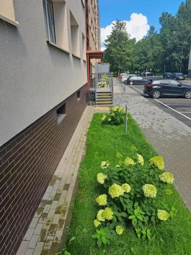 a building with a flower garden next to a street at Ąžuolų giraitėje 2 bedroom apartments in Klaipėda