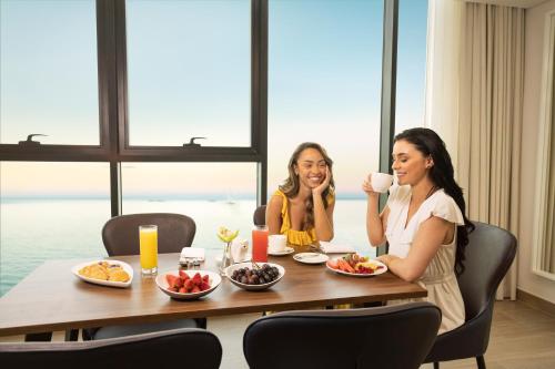 two women sitting at a table drinking coffee at Beach Bay Hotel Mirfa in Al Marfaʼ