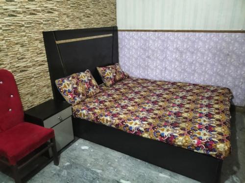 a bedroom with a bed and a red chair at New Taj Hotel in Lahore