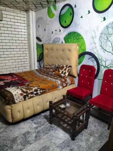 a bedroom with a bed and two red chairs at New Taj Hotel in Lahore