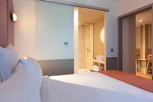a bedroom with a white bed and a bathroom at lyf Gambetta Paris in Paris
