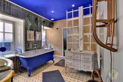 La salle de bains est pourvue d'une baignoire bleue et d'un lavabo. dans l'établissement La goutte d'or, à Combourg