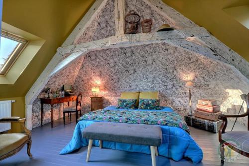 une chambre avec un lit avec un mur en pierre dans l'établissement La goutte d'or, à Combourg