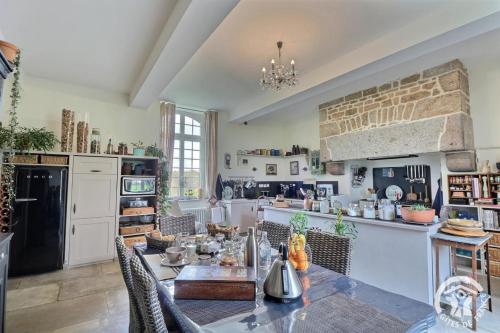 a kitchen with a dining table and a brick wall at La gentilhommiere in La Bazouges-du-Désert