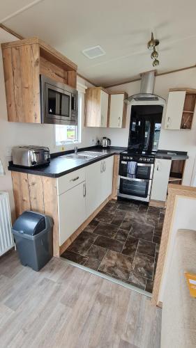 a kitchen with white cabinets and black counter tops at Hoburne Devon Bay Fabulous 3 bedroom caravan, with decking in Goodrington