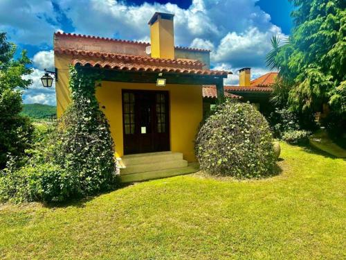a small yellow house with a door in a yard at Quinta do Pomarinho - by RowdHouses in Arouca