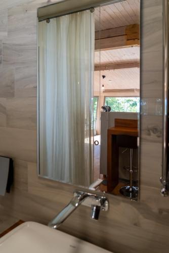 a bathroom with a mirror and a sink and a fireplace at Guest House Vidlauči in Skulte