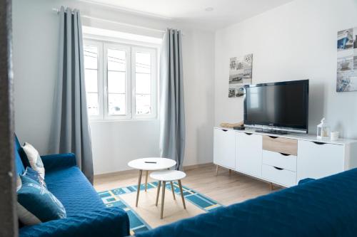 a living room with a blue couch and a tv at Casa do Porto in Angra do Heroísmo