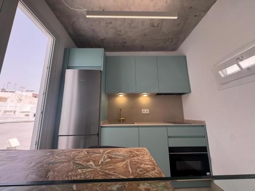 a kitchen with blue cabinets and a stainless steel refrigerator at Estudio Boutique Mar de Bering in Conil de la Frontera