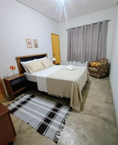 a bedroom with a large bed and a couch at Chácara Por do Sol in Pouso Alegre