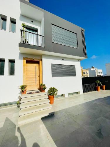 a white house with a door and a balcony at Luxury house in Martil in Martil