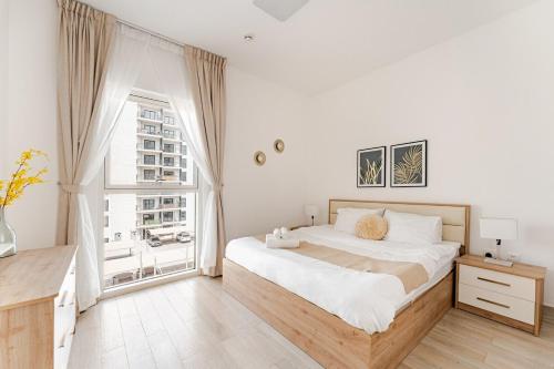 a white bedroom with a large bed and a window at Sleek Stays - 1BR with balcony at Yas Island near Sea World,Etihad Arena in Abu Dhabi