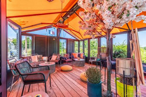 a deck with chairs and tables and a tree at Restaurant Hotel Didier Méril in Dinard
