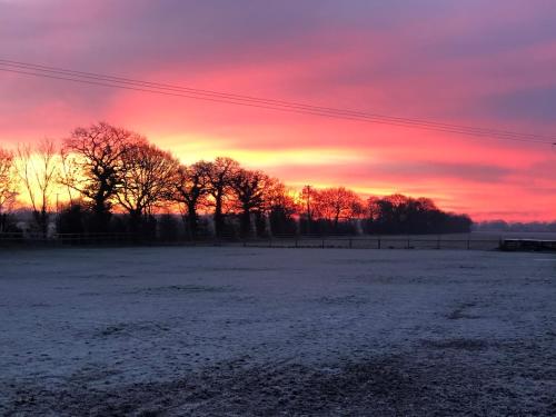 a snowy field with a sunset in the background at Arglam Lane Farm - 4 bedroom Tranquil Countryside Retreat sleeps 7 in Holme upon Spalding Moor