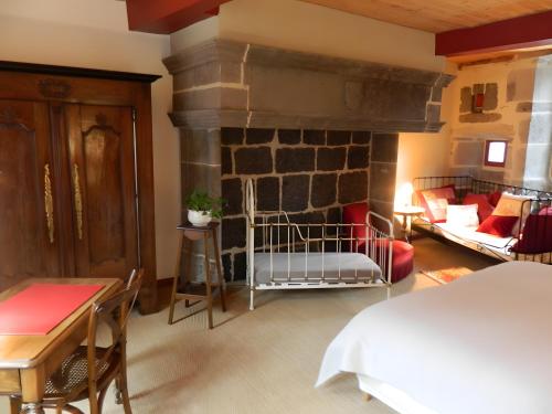 a bedroom with a stone fireplace with a bed and a couch at La Maison De Marie in Murat