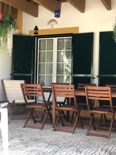 three wooden chairs and a table on a patio at Casa da Oliveira in Vila Nova de Milfontes